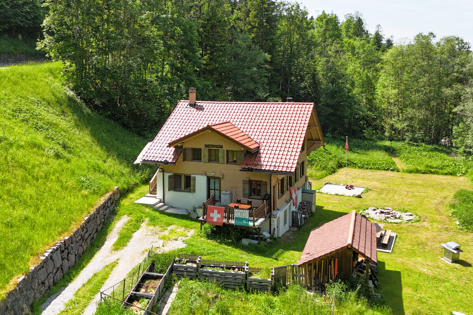 outdoor house featuring a tiled roof, a chimney, driveway, and a view of trees