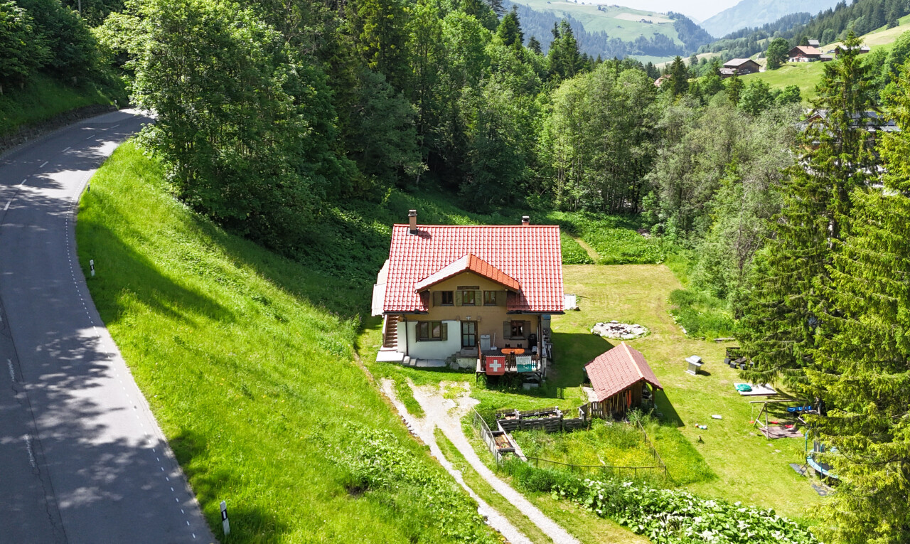 outdoor house with a chimney, a view of trees, a mountain view, and a tiled roof
