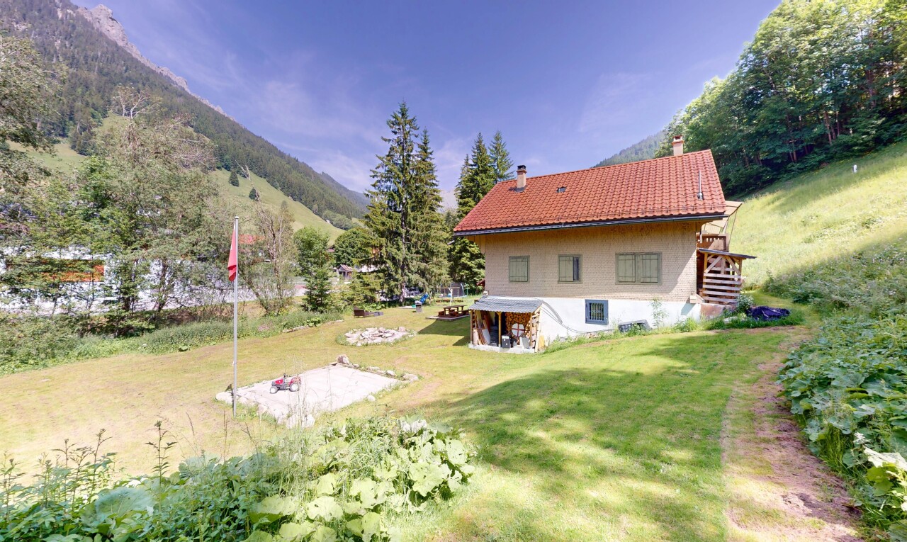 outdoor house with a chimney, a mountain view, a lawn, stairway, and a tiled roof