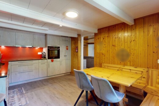 kitchen with beamed ceiling, wooden walls, oven, light wood-style floors, and dark countertops