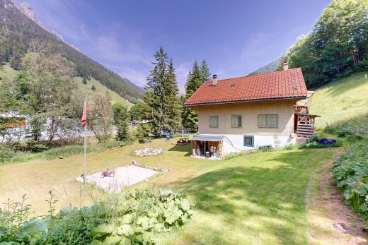 façade avec cheminée, mountain view, vue sur la montagne, pelouse, et property visible