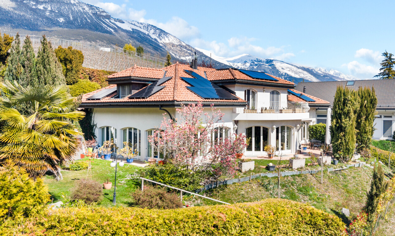 outdoor house featuring a mountain view, a patio area, solar panels, stucco siding, and a lawn