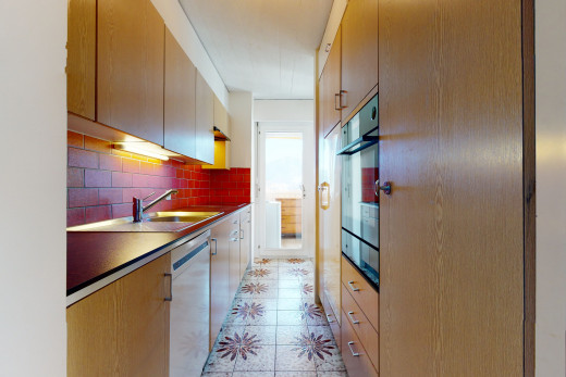 küche mit ofen, geschirrspüler aus edelstahl, braunen schränken, dunklen arbeitsplatten und hellen fliesenböden