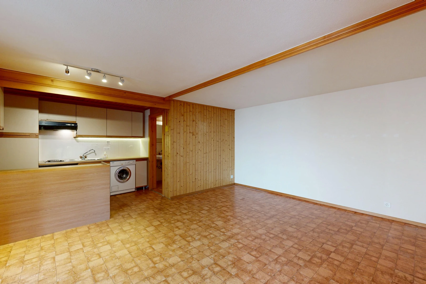 empty room featuring rail lighting, wooden walls, and washer / clothes dryer