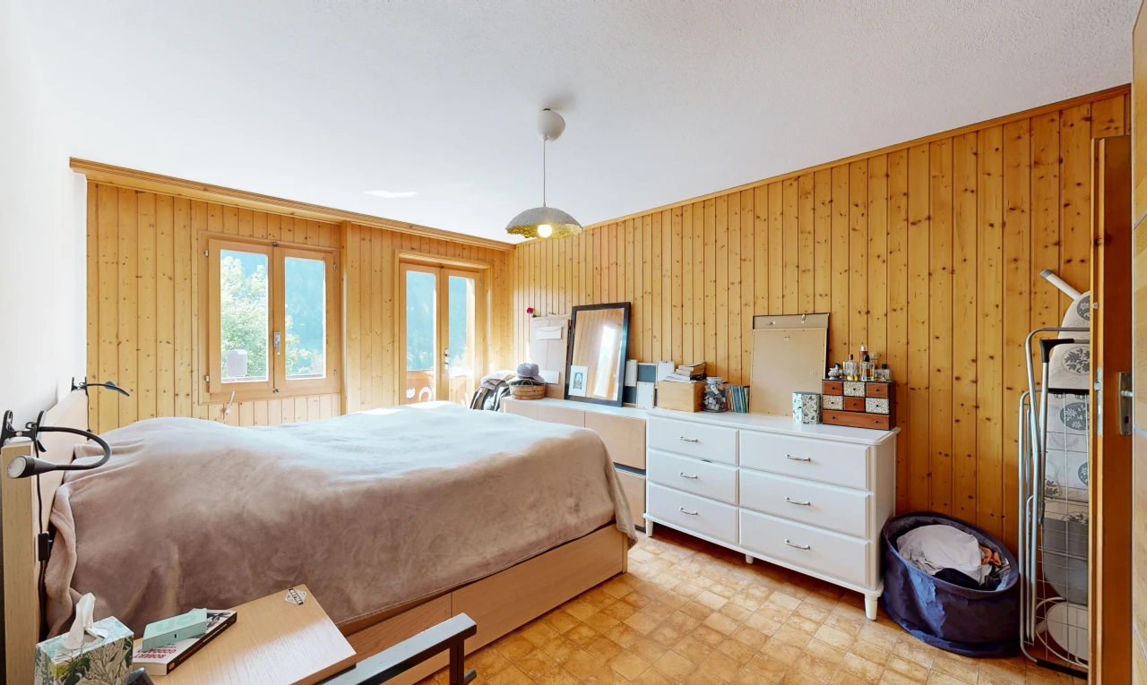room / bedroom featuring wood walls, decorative light fixtures, and light floors