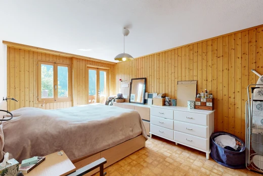room / bedroom featuring wood walls, decorative light fixtures, and light floors
