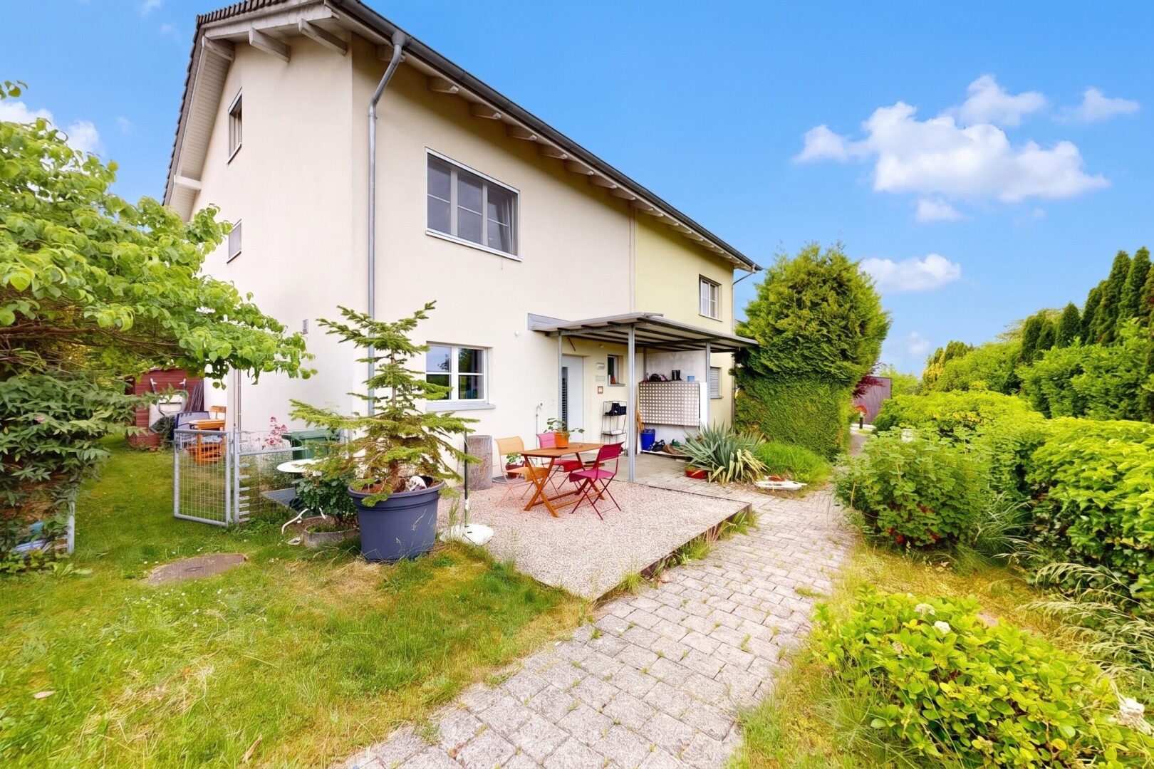 façade avec property visible, terrasse, bardage en stuc, pelouse, et day time