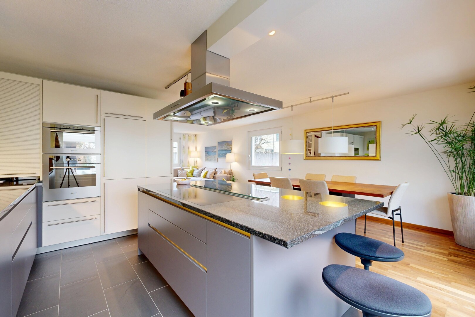 kitchen featuring island range hood, a kitchen bar, a kitchen island, light stone counters, and two tone cabinets