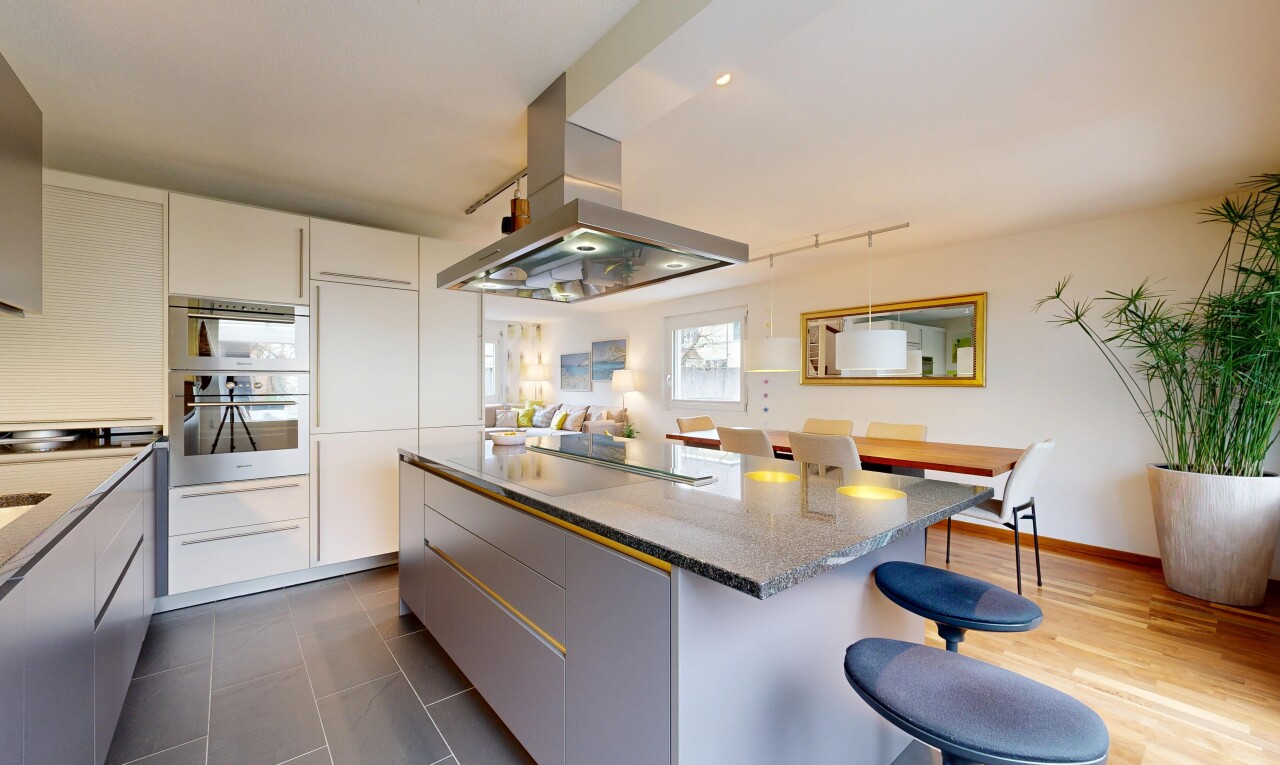 kitchen featuring island range hood, a kitchen bar, a kitchen island, light stone counters, and two tone cabinets