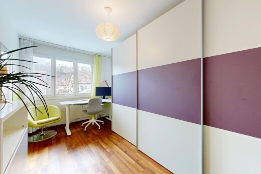chambre avec espace bureau, sol en finition bois, wood finish floor, inside property, et télévision
