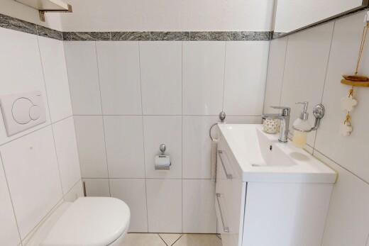 salle de bains avec tile wall, mur en carrelage, lavabo (ou coiffeuse selon le contexte), toilette, et inside property
