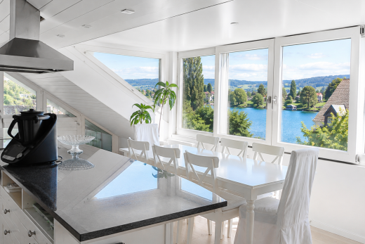 kitchen with island range hood, white cabinets, a water view, dark stone counters, and a kitchen island