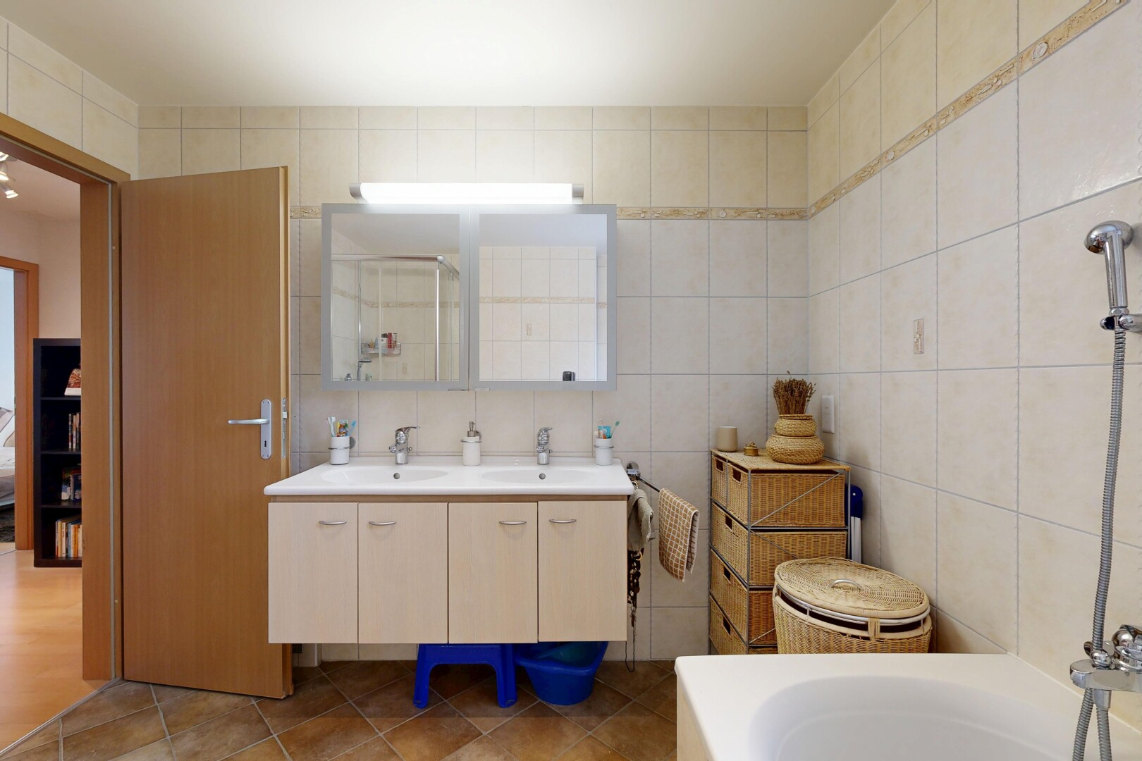 full bathroom with double vanity, tile walls, a tub, and dark tile patterned flooring