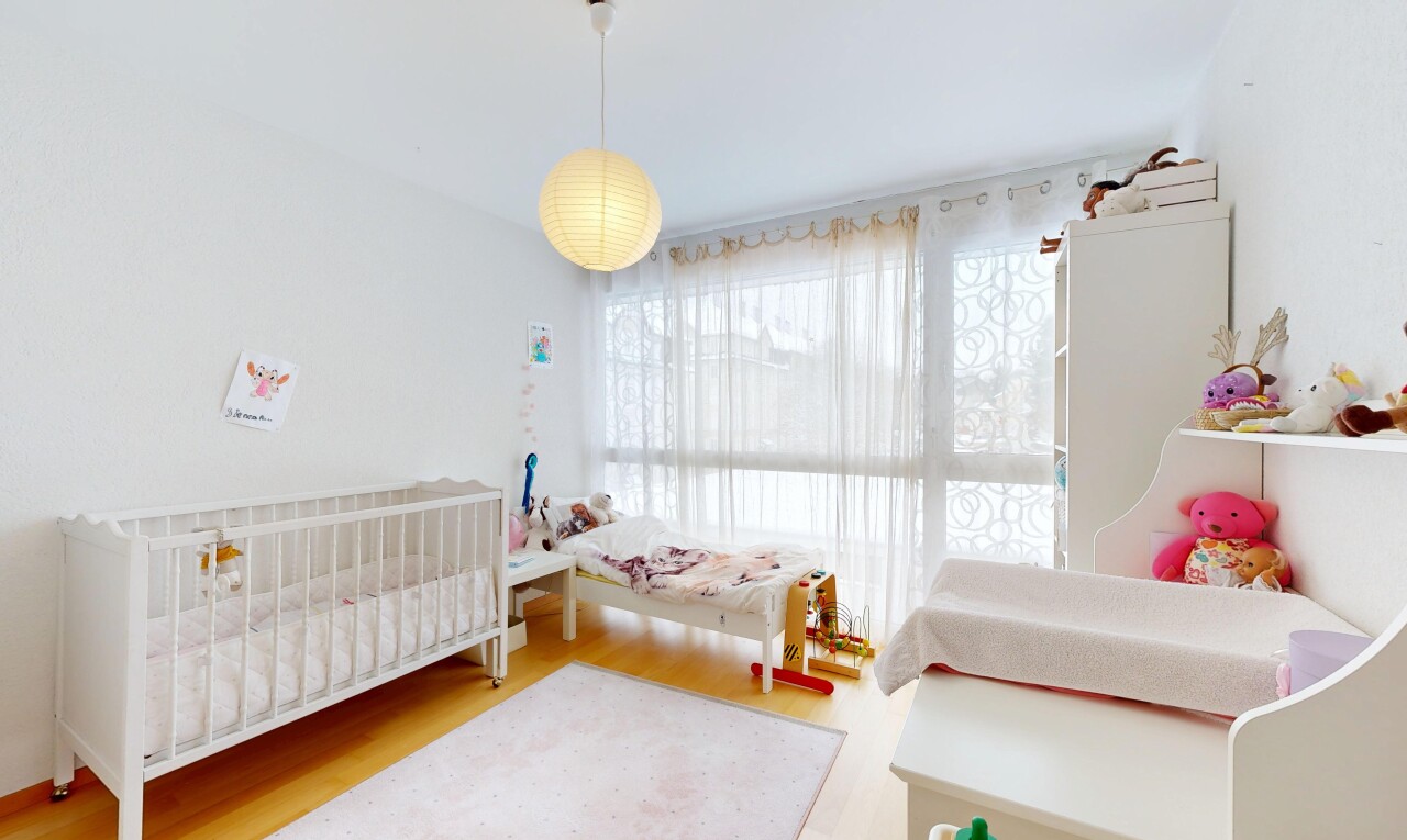 room / bedroom featuring a crib and wood finished floors