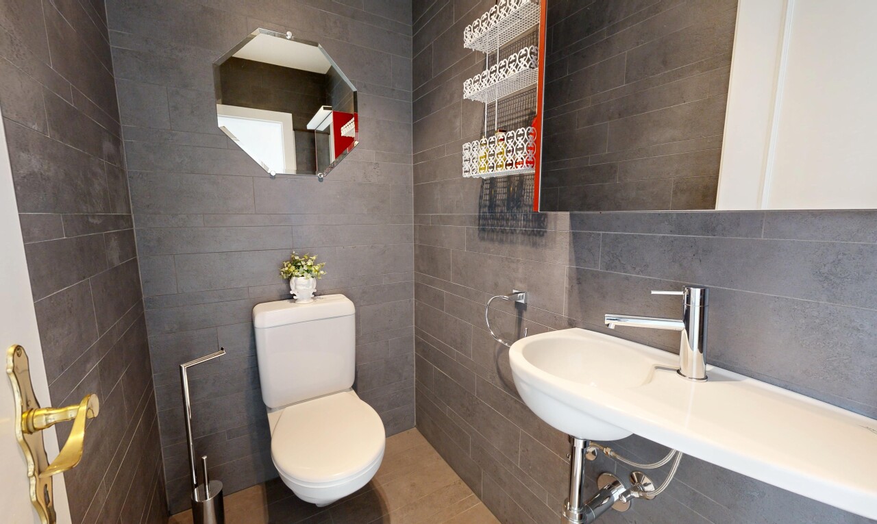 bathroom with toilet and tile walls