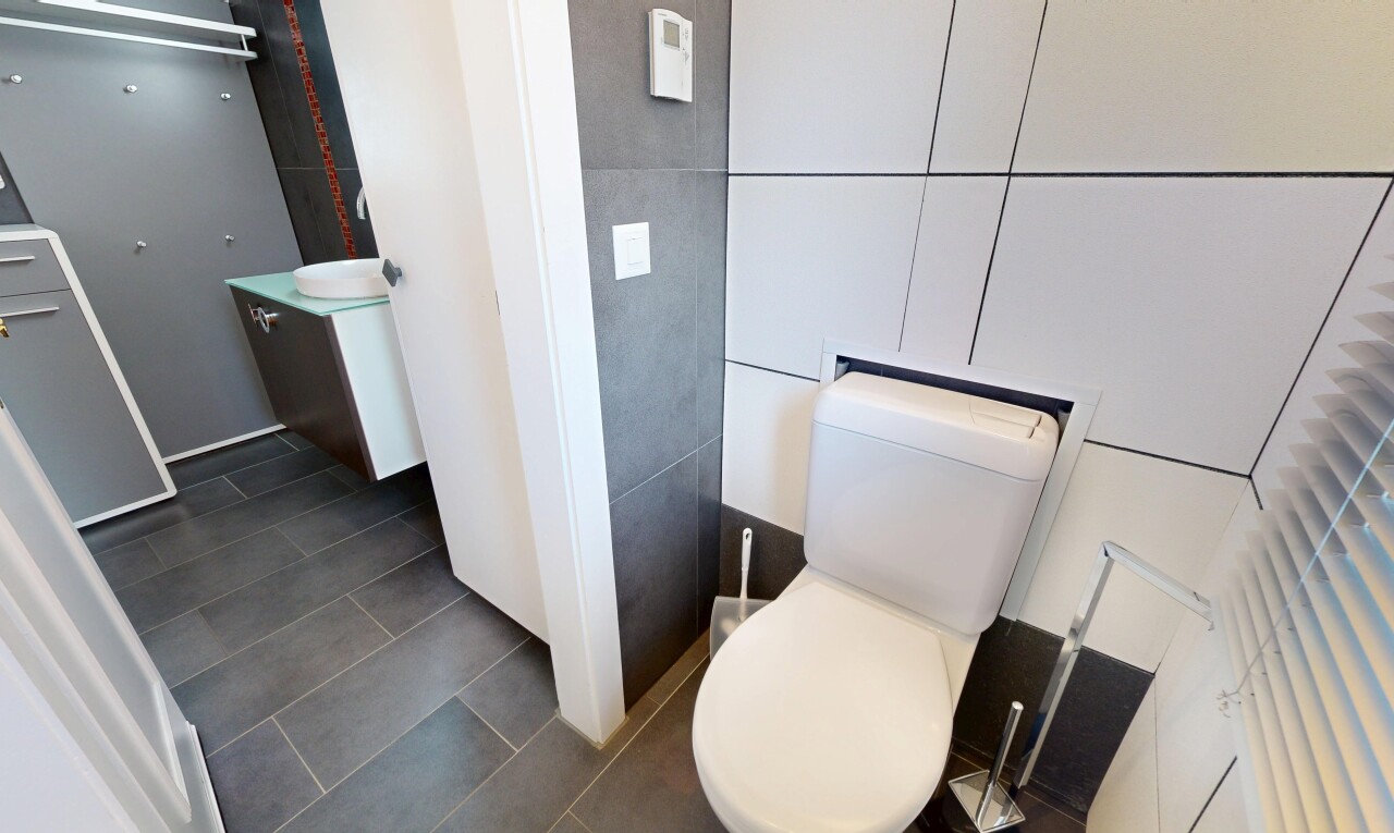half bath featuring vanity, dark tile patterned flooring, and tile walls
