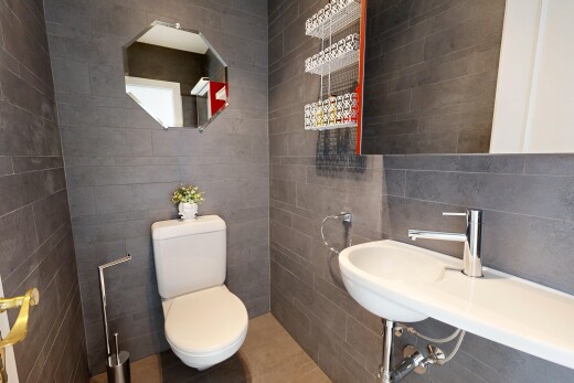 salle de bains avec miroir, toilette, inside property, évier, et tile wall