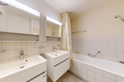 bathroom with two vanities, tile walls, and tiled shower / bath