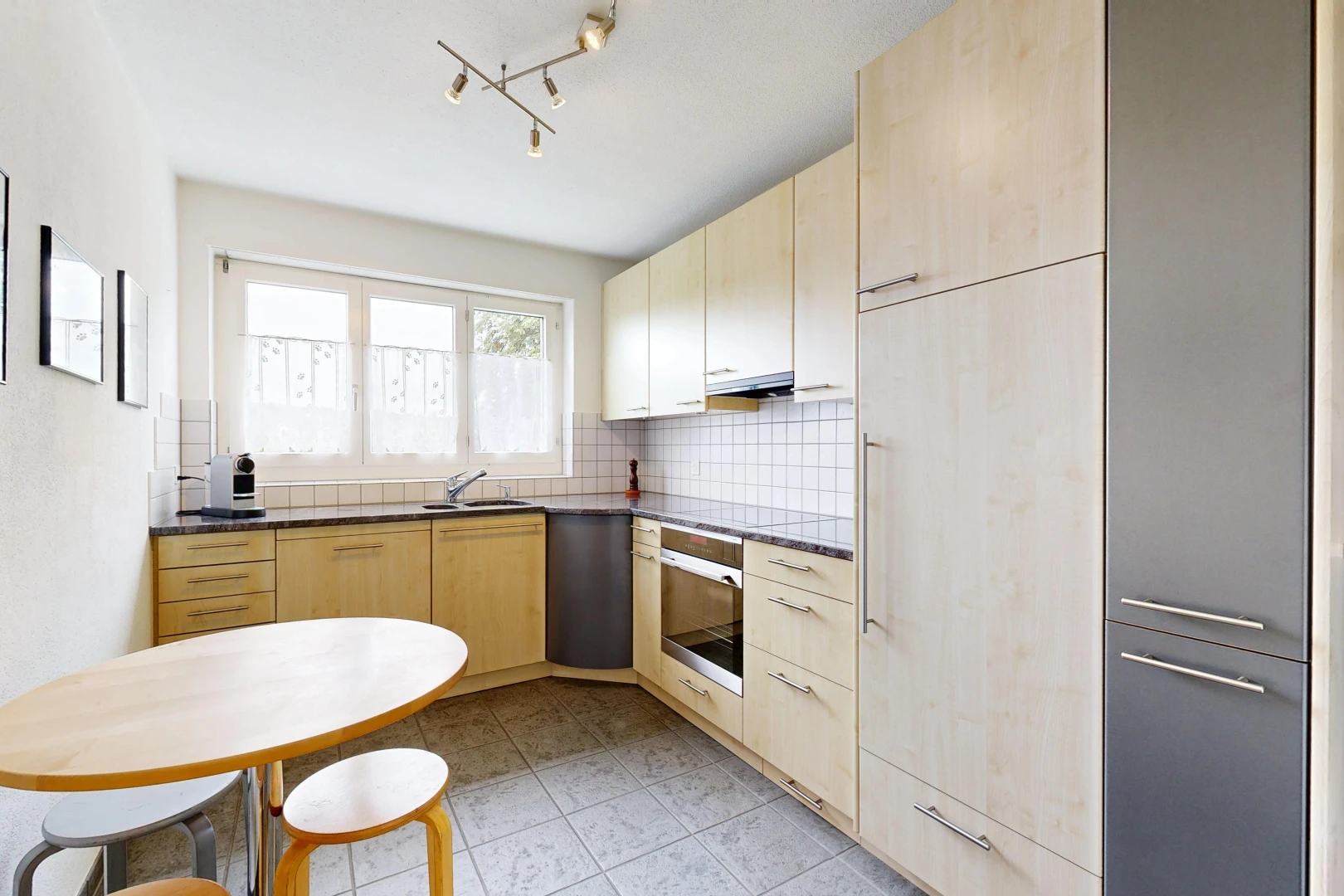cuisine avec dark countertops, armoires marron clair, light brown cabinets, éclairage sur rail, et light floor