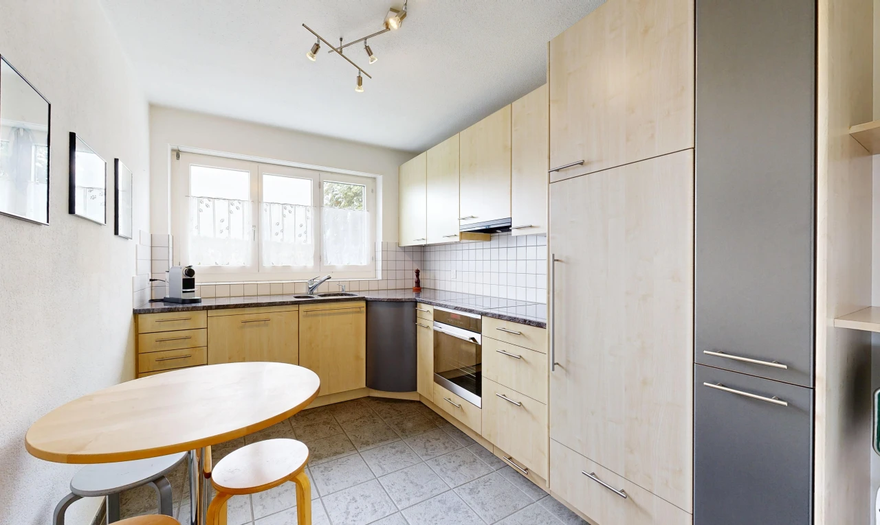 cuisine avec dark countertops, armoires marron clair, light brown cabinets, éclairage sur rail, et light floor