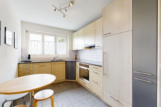 cuisine avec dark countertops, armoires marron clair, light brown cabinets, éclairage sur rail, et light floor