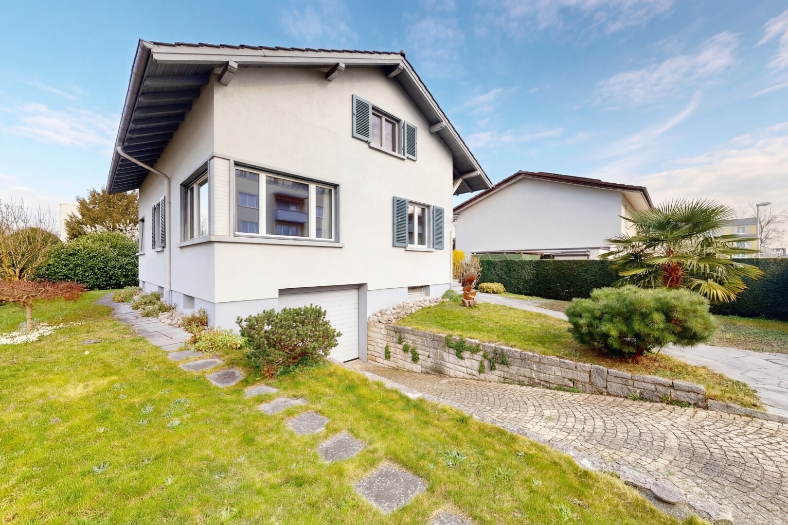 außenansicht mit rasen, stuckverkleidung, property visible, eingebaute garage, und kellergarage