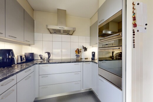 cuisine avec hotte, dark countertops, four, backsplash, et dosseret
