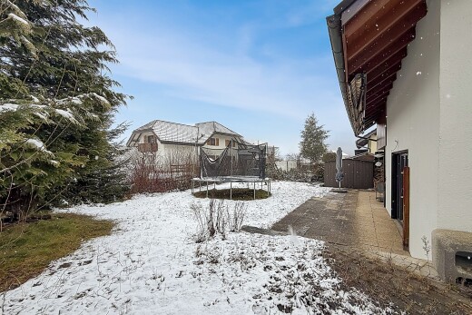 snow covered house featuring a trampoline and stucco siding