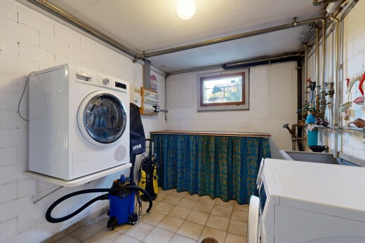 laundry area featuring concrete block wall and light tile patterned floors