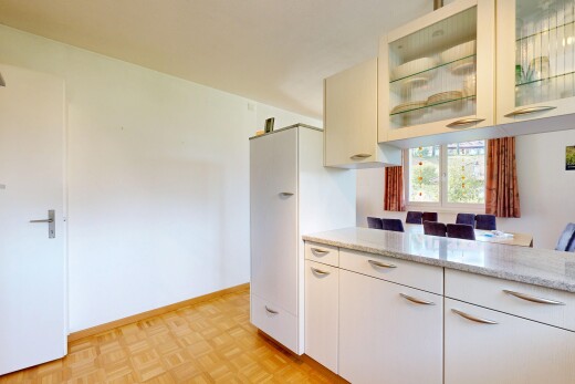 kitchen featuring glass fronted cabinets, parquet flooring, light stone counters, and freestanding refrigerator