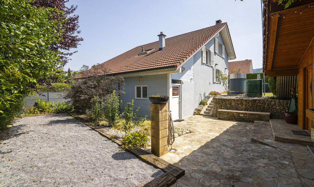 outdoor house with a patio area, a tile roof, stucco siding, and a chimney