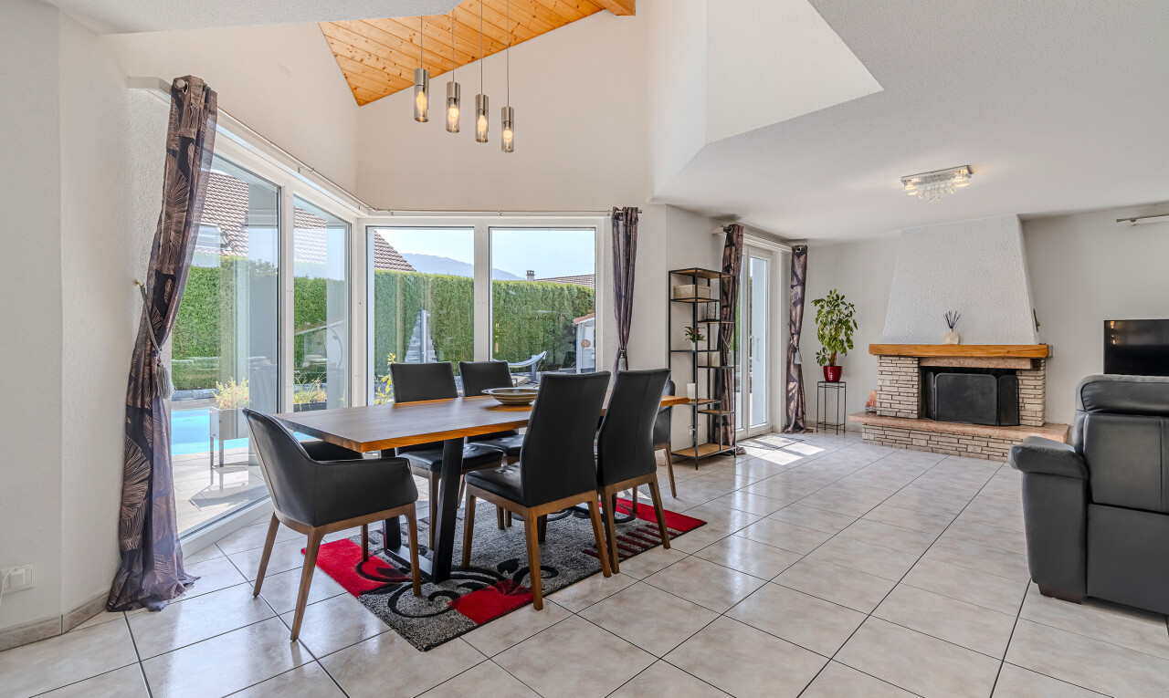 living / dining room with a fireplace with raised hearth, high vaulted ceiling, beamed ceiling, and light tile patterned floors