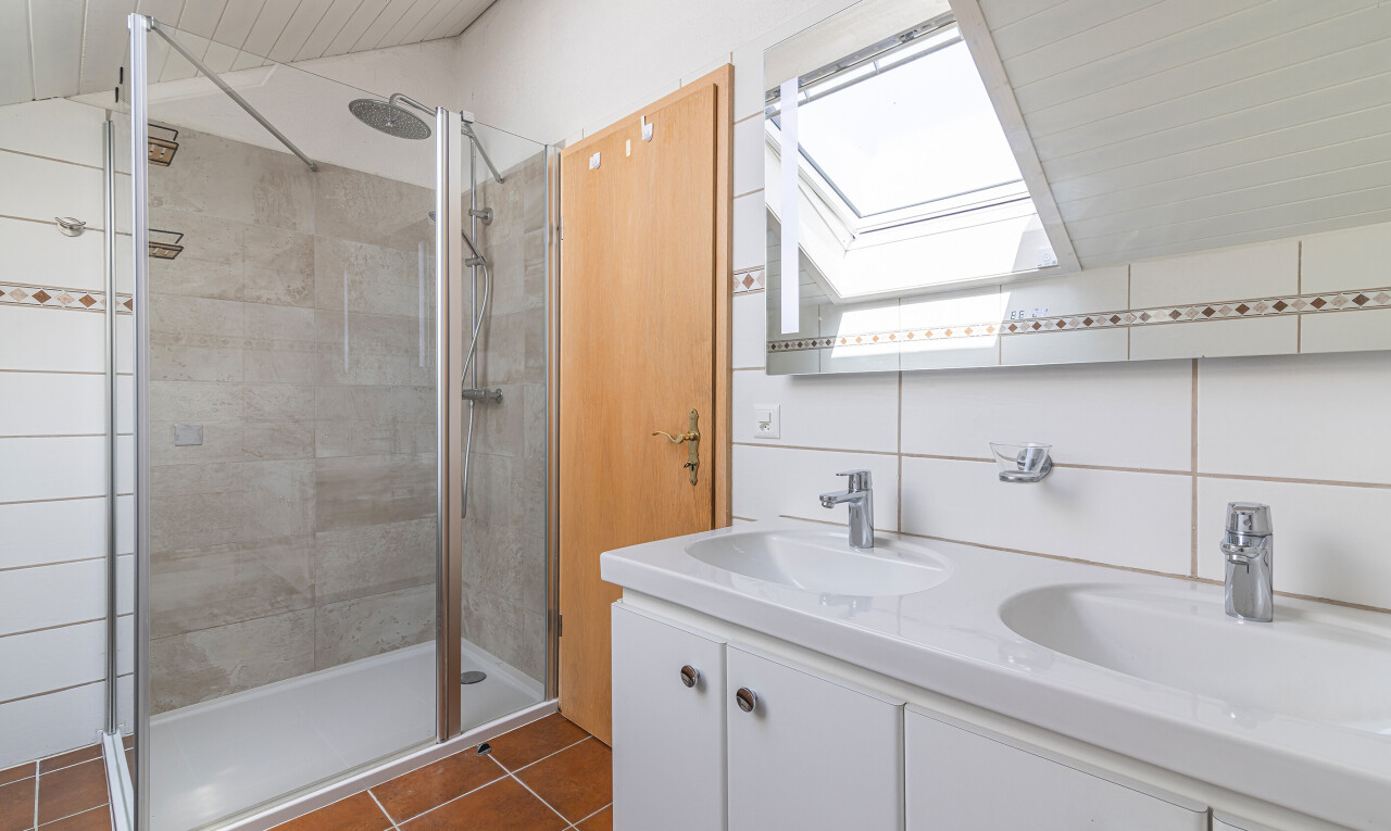 bathroom featuring double vanity, a shower stall, dark tile patterned floors, a skylight, and lofted ceiling