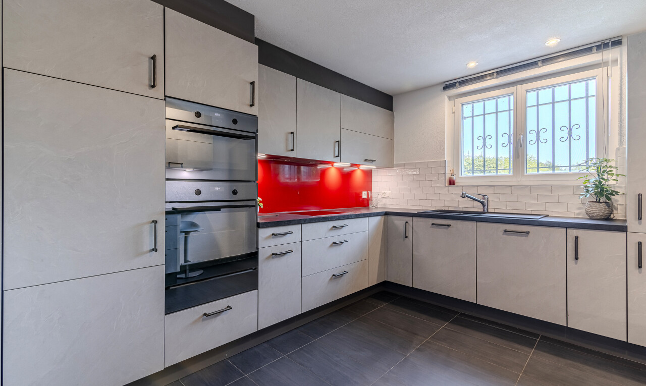 kitchen with multiple ovens, backsplash, dark tile patterned floors, dark countertops, and white cabinetry