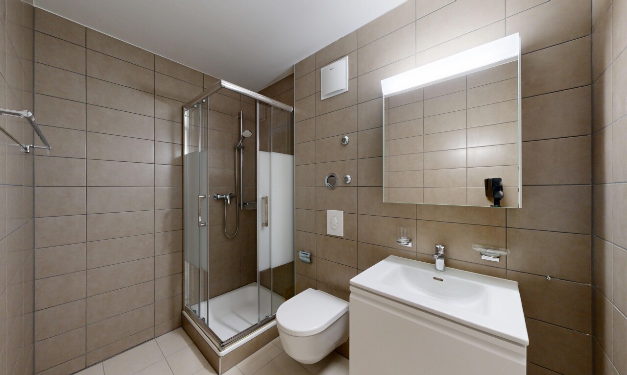 full bathroom with tile walls, a stall shower, vanity, and light tile patterned floors