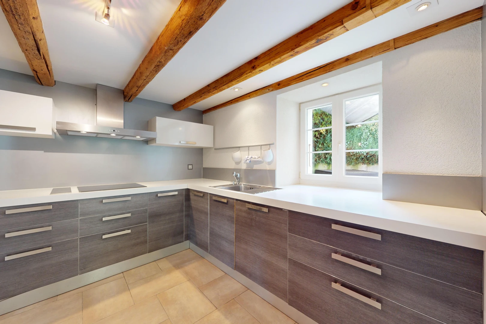 kitchen featuring beamed ceiling, sink, dark brown cabinets, wall chimney exhaust hood, and white cabinetry