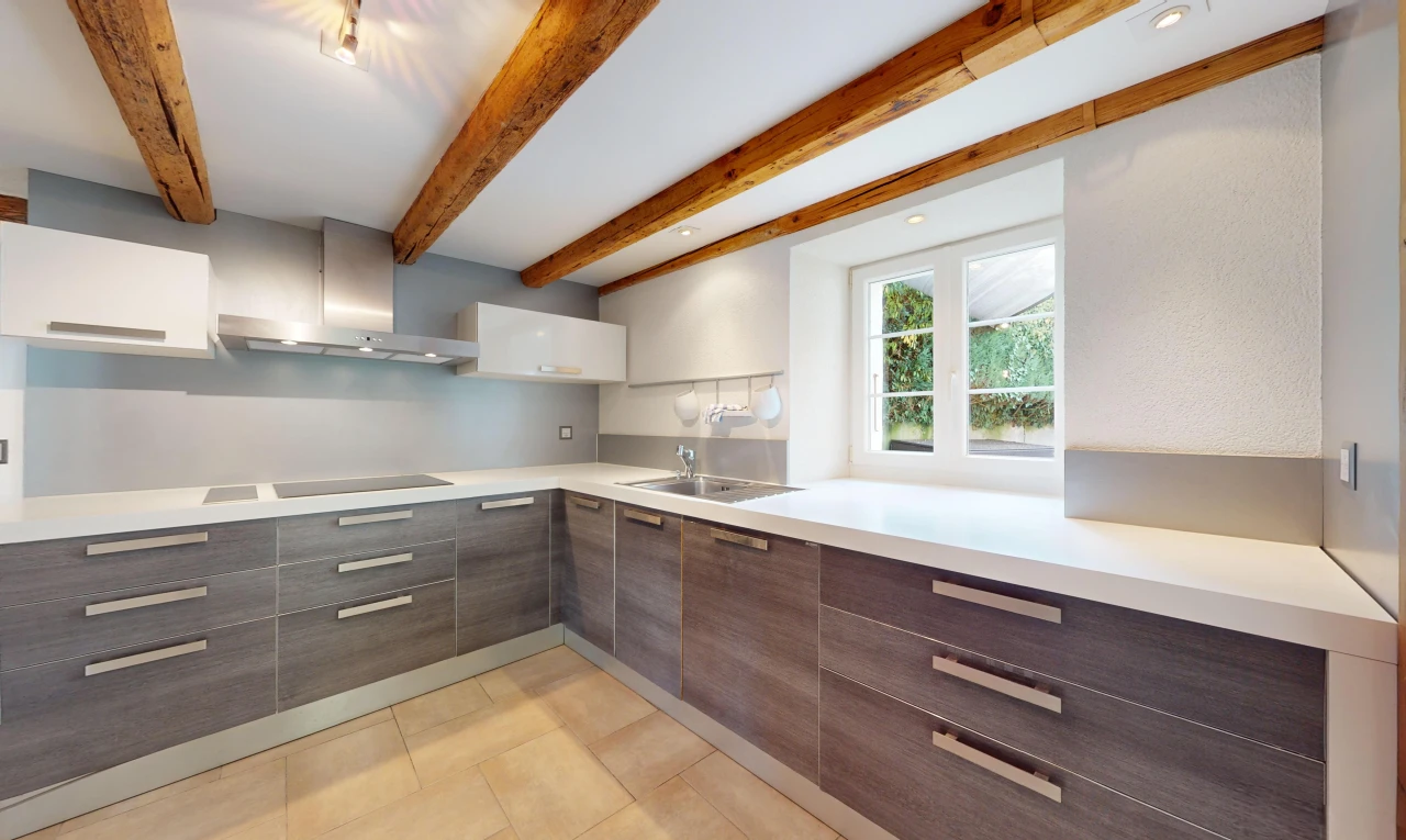 kitchen featuring beamed ceiling, sink, dark brown cabinets, wall chimney exhaust hood, and white cabinetry