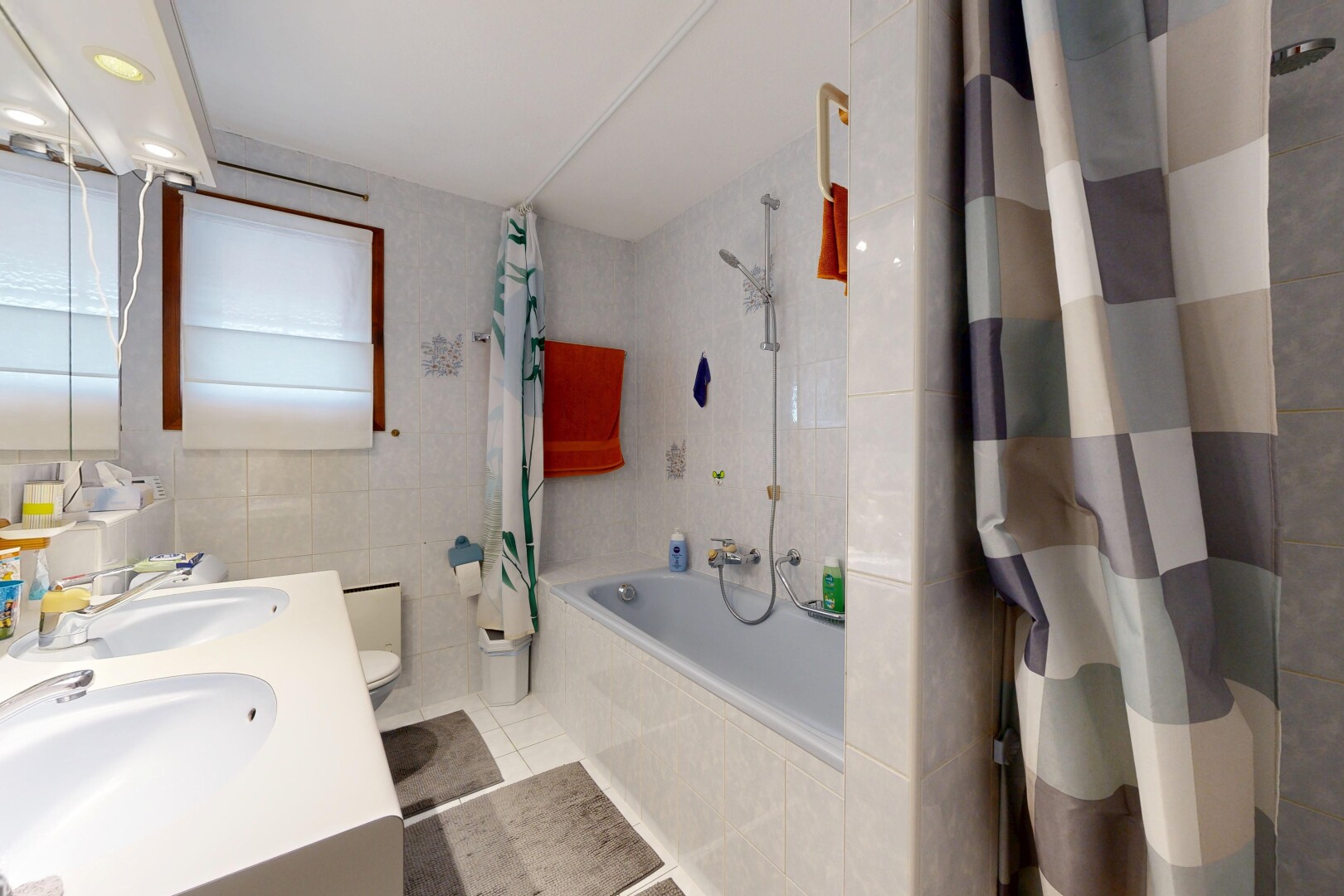 full bath featuring tiled shower / bath, tile walls, double vanity, and light tile patterned floors