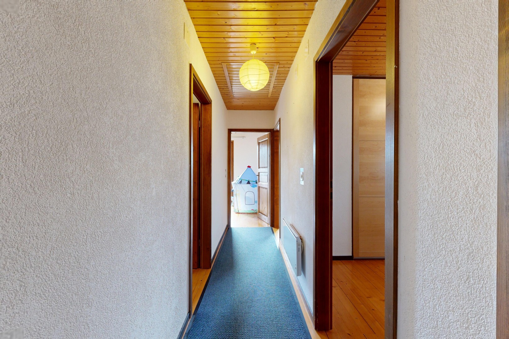 hall with a textured wall, wood ceiling, and light carpet