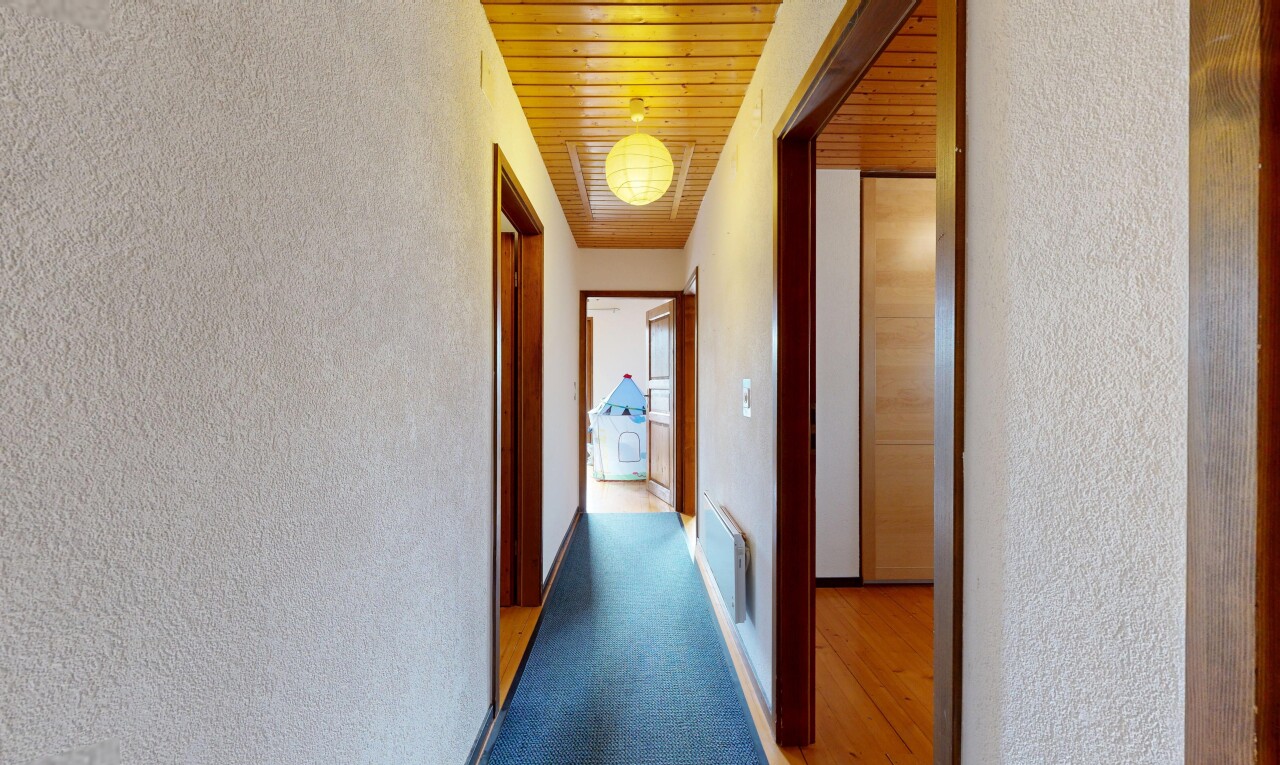hall with a textured wall, wood ceiling, and light carpet