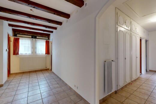 empty room featuring radiator heating unit, radiator, light tile patterned floors, beam ceiling, and arched walkways