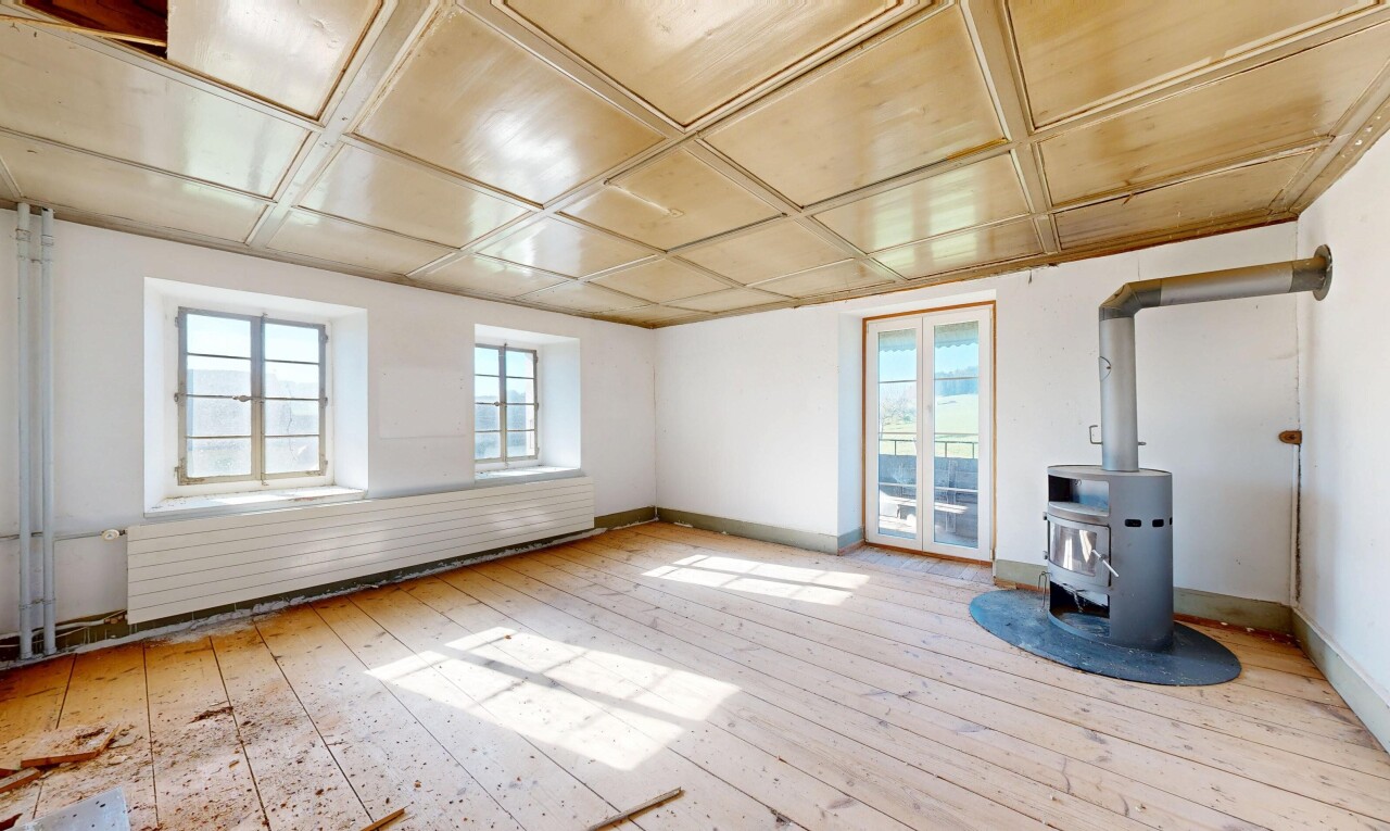 pièce vide avec drywall, cloison sèche, poêle à bois, inside property, et wood finish floor
