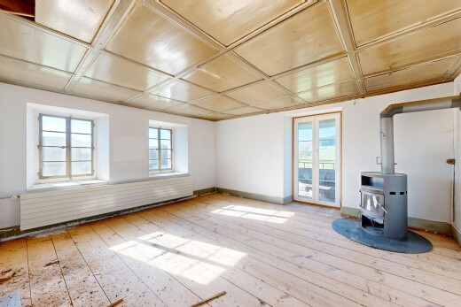 pièce vide avec drywall, cloison sèche, poêle à bois, inside property, et wood finish floor