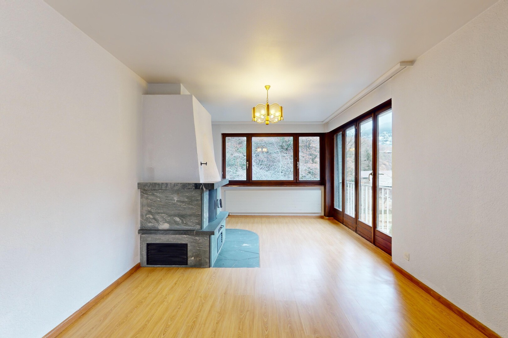 leerer raum mit kamin, parkettboden, natürliches licht, bemerkenswerter kronleuchter, und kronenstuck