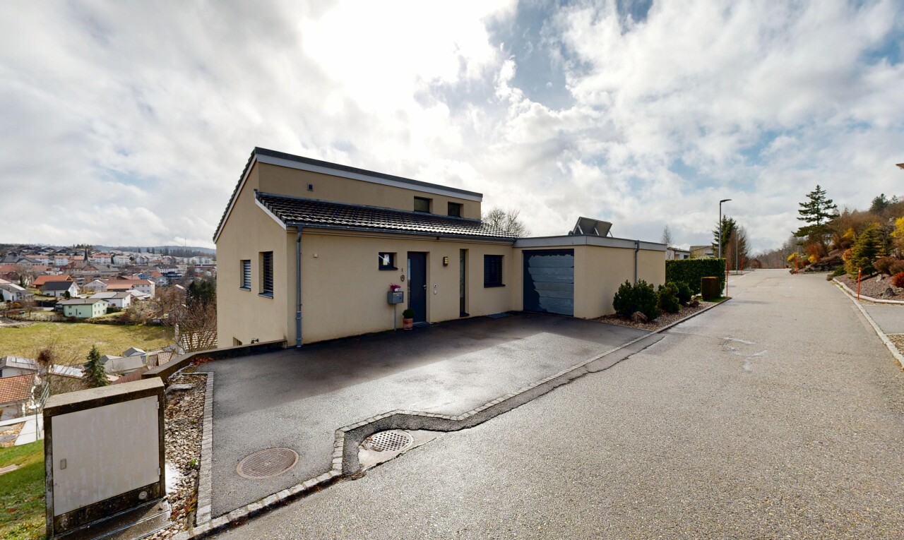 façade avec bardage en stuc, property visible, garage attaché, allée, et day time
