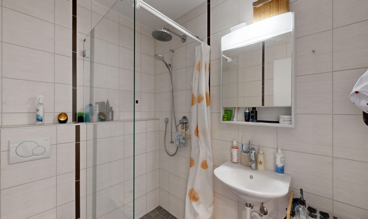 salle de bains avec miroir, salle de bain complète, douche, inside property, et mur en carrelage
