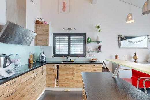cuisine avec plans de travail, dark countertops, armoires marron clair, light brown cabinets, et hotte