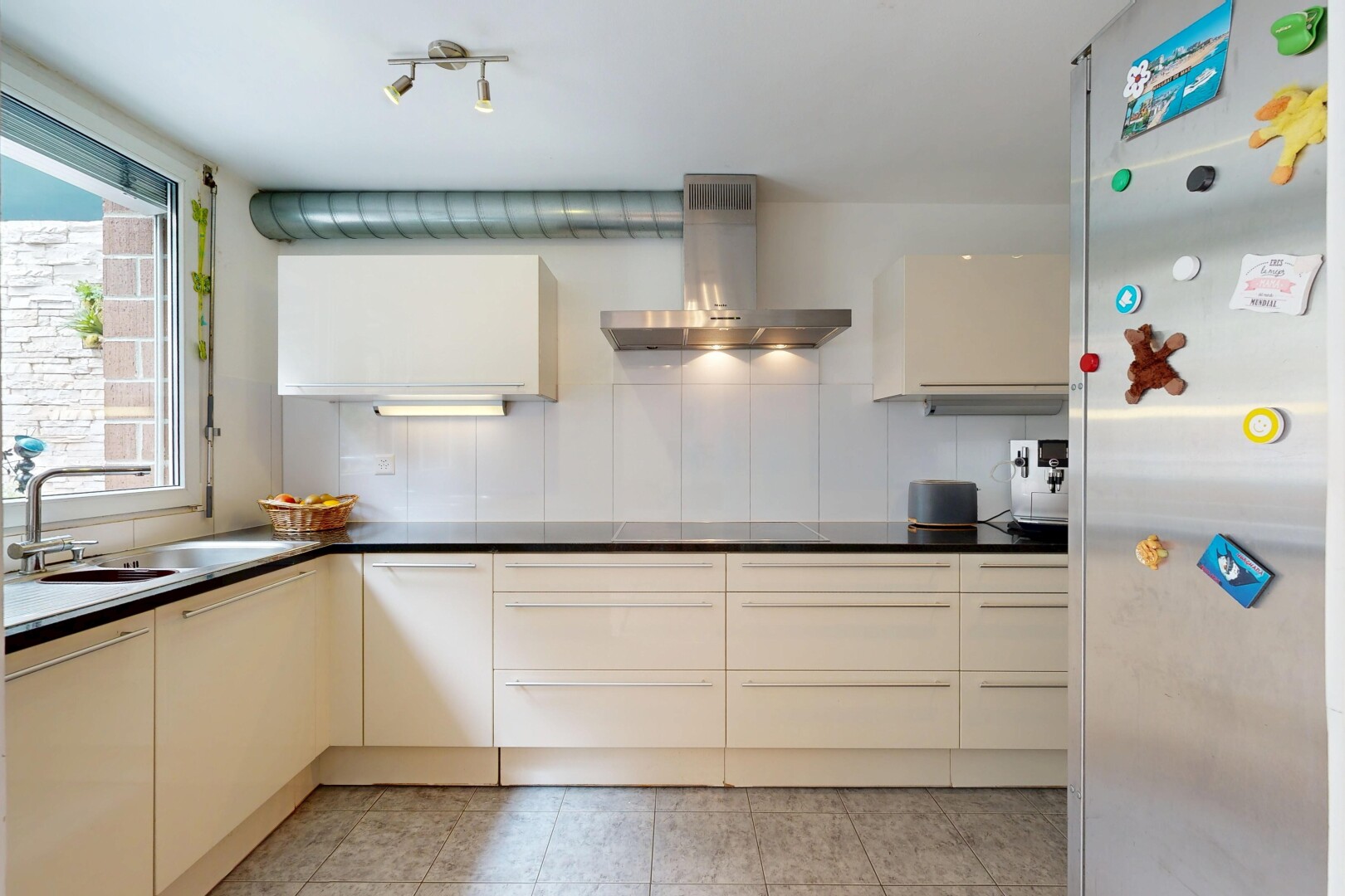 kitchen featuring fridge, dark countertops, cream cabinets, modern cabinets, and backsplash