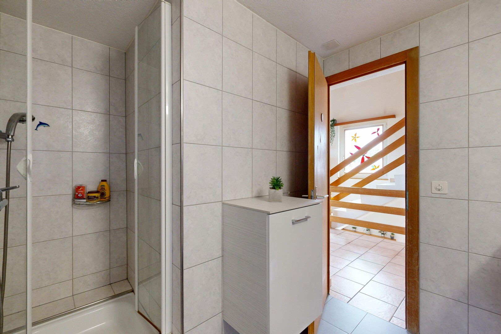 full bath featuring tile walls, a shower stall, and light tile patterned floors