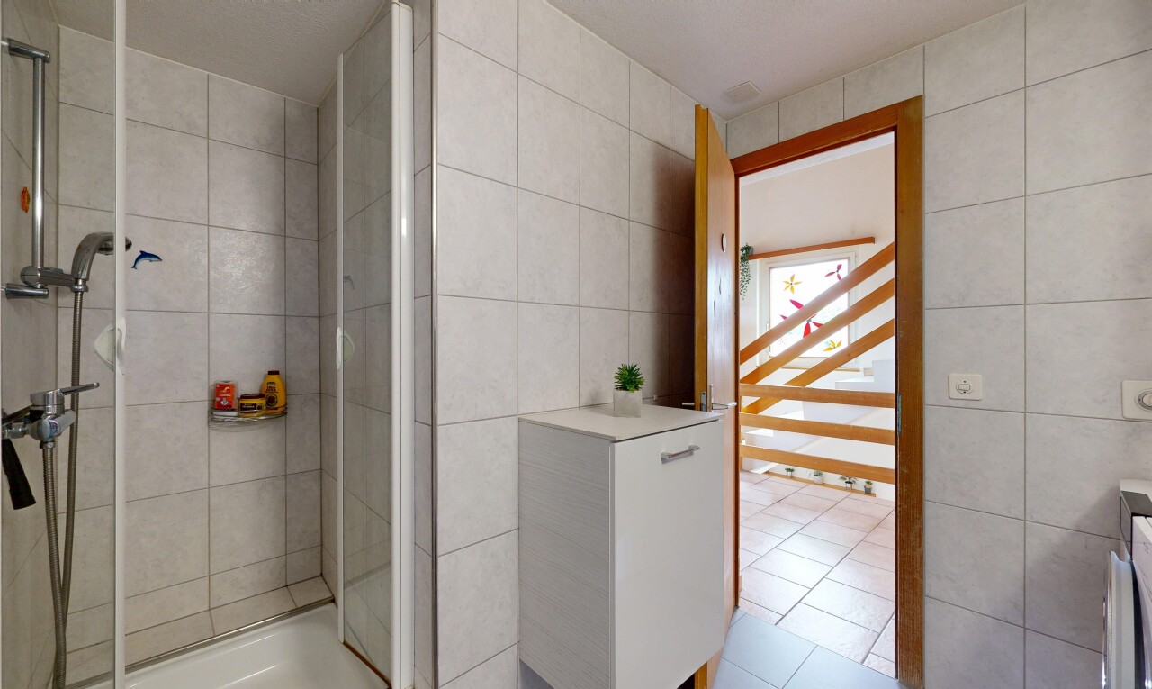 full bath featuring tile walls, a shower stall, and light tile patterned floors